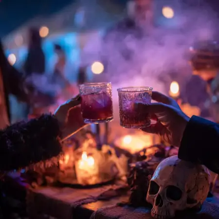 Guests toasting Halloween cocktails at a spooky Texas party with candles and fog