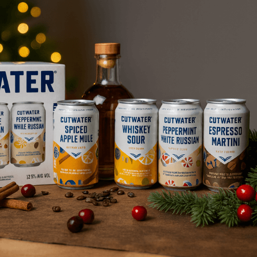 Cutwater cans and a whiskey bottle arranged on a warm holiday bar counter with Christmas decor.
