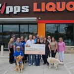 ipps Liquor Quitman team and Quitman-Lake Fork Kiwanis Club volunteers holding $865 donation check in front of the store at 350 Richards Street Quitman Texas with two dogs April 2026