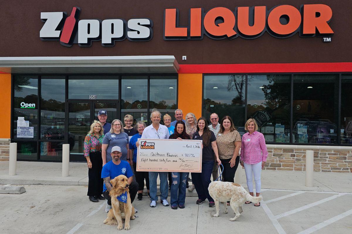 ipps Liquor Quitman team and Quitman-Lake Fork Kiwanis Club volunteers holding $865 donation check in front of the store at 350 Richards Street Quitman Texas with two dogs April 2026