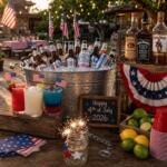 July 4th Party Planning Guide: Texas Liquor, Beer, and Cocktails for Independence Day 2026 July 4th party drink setup with red white blue cocktails beer buckets and American flags in Texas backyard