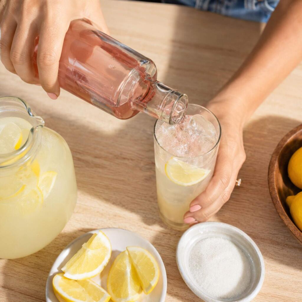 Lemonade Day: Spiked Vodka and Tequila Lemonade for the Texas Heat Bartender pouring flavored vodka into a glass of fresh lemonade over ice